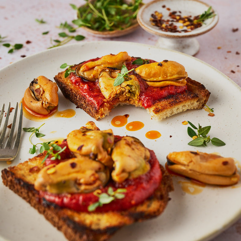 2 pieces of chargrilled sourdough topped with a spiced tomato sauce and some pickled mussels