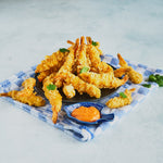 Tempura Prawns arranged in a tower on a black plate with a dipping sauce